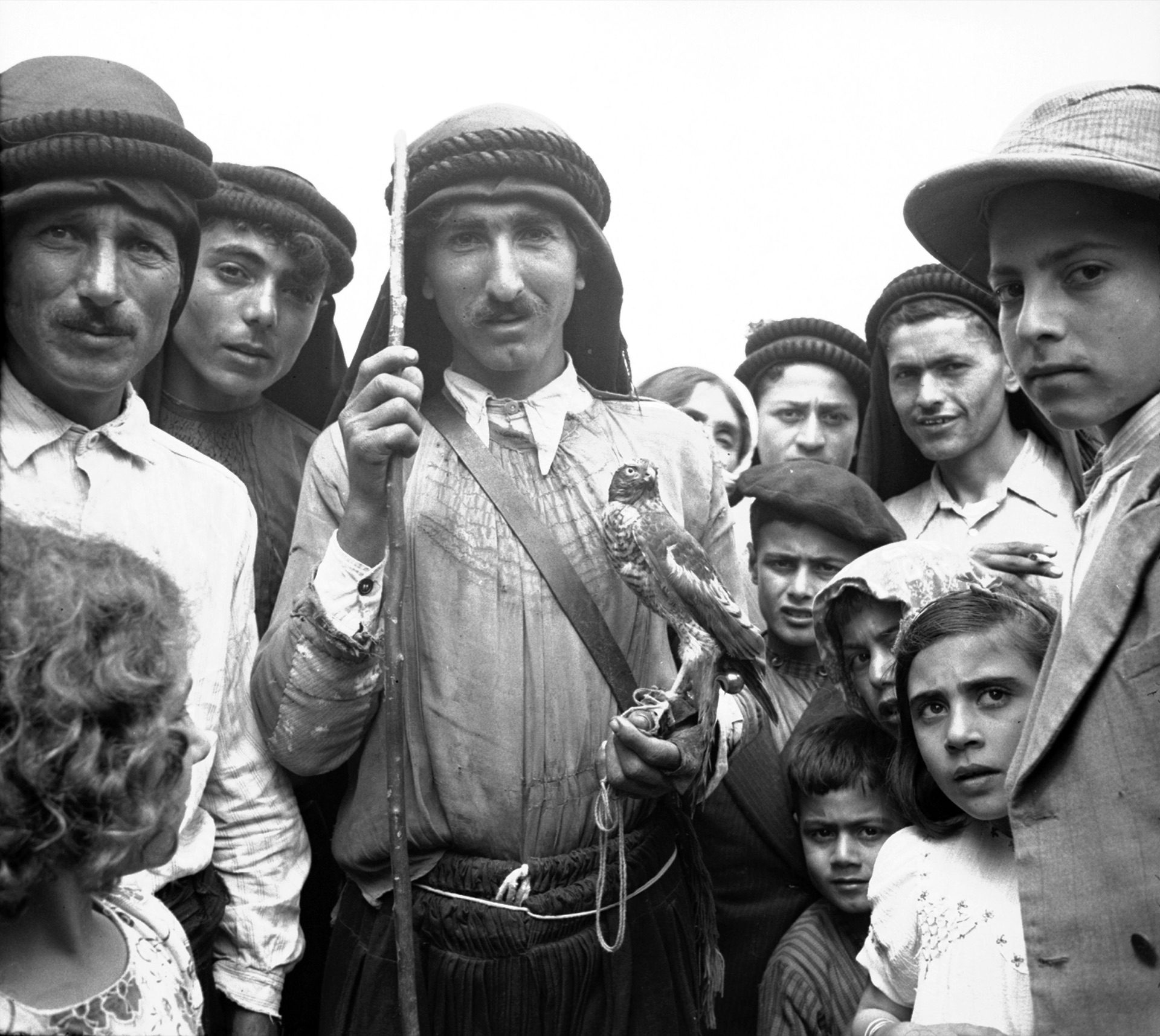Historic photograph of a group of villagers of the coastal mountains, a falcon on one man's hand