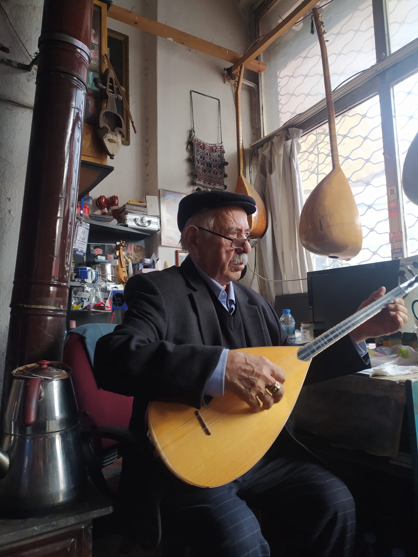 A bağlama maker in his workshop playing an instrument he has repaired