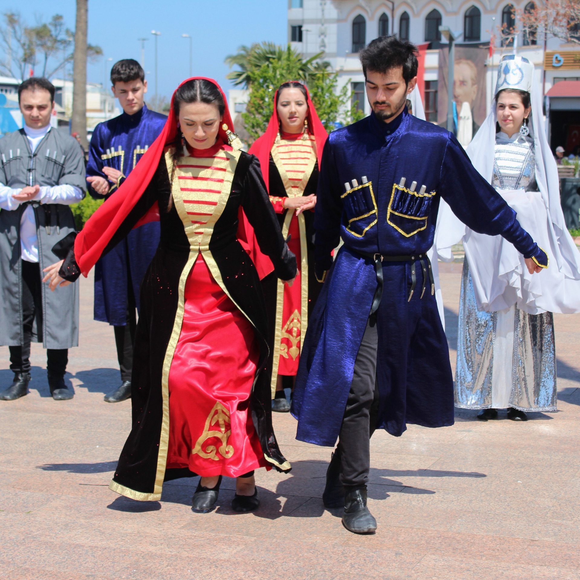 Circassian dancers in red and blue cherkeska coats performing a folk dance