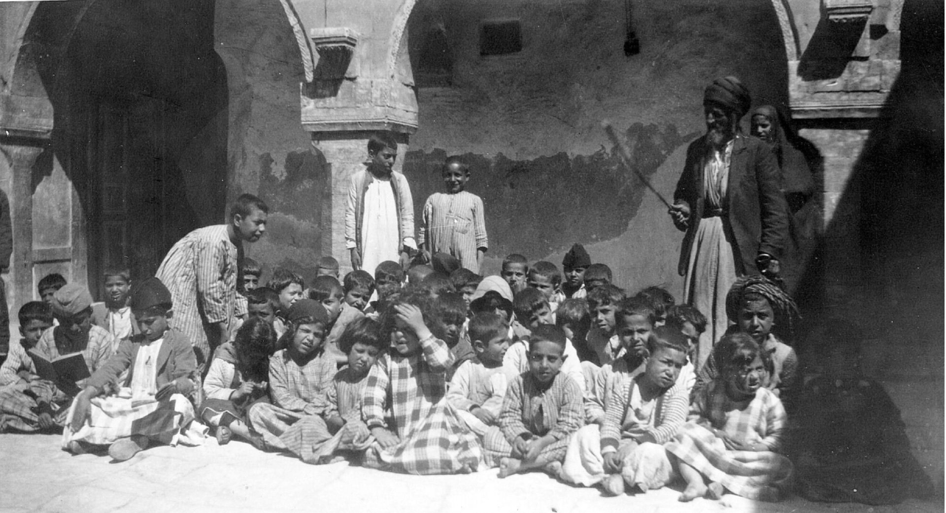 Jewish schoolchildren seated in a courtyard with their teacher, Mosul, Iraq