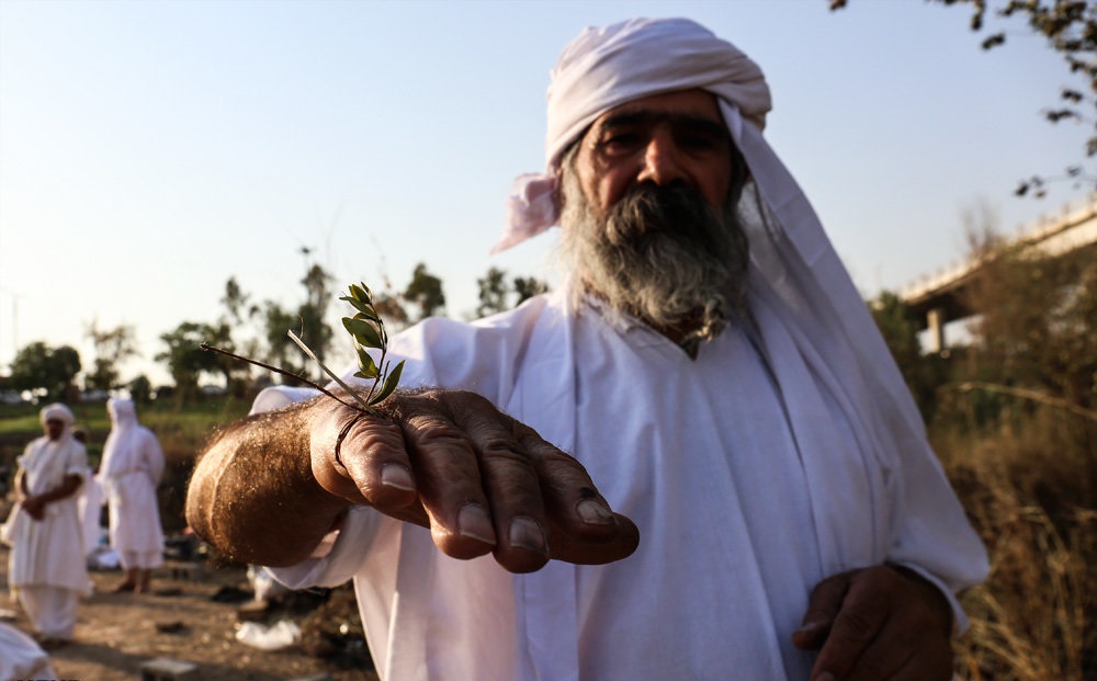 A Mandaean priest immersing a worshipper in the river during masbuta