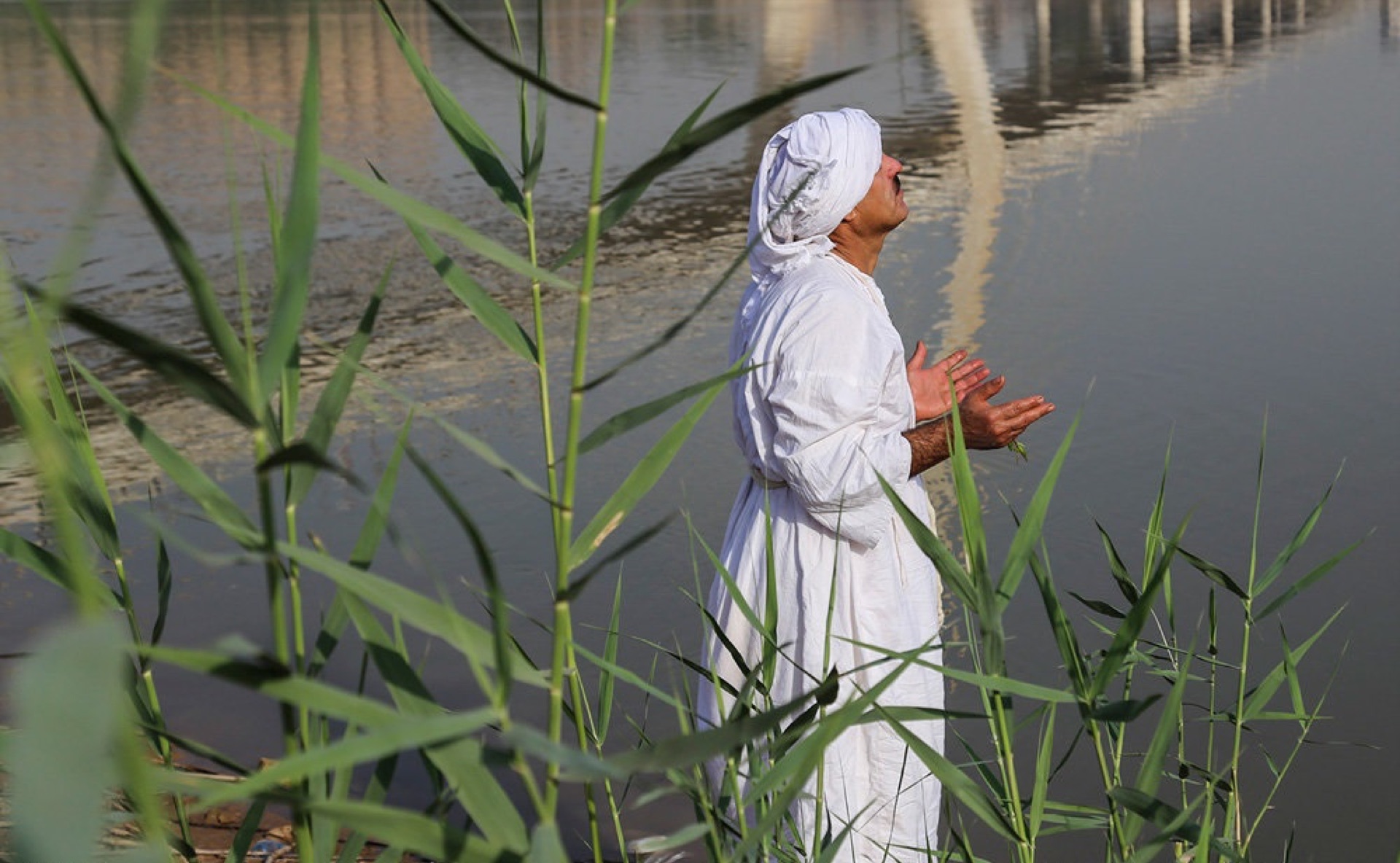 Mandaean priests in white robes performing masbuta together in the Karun river