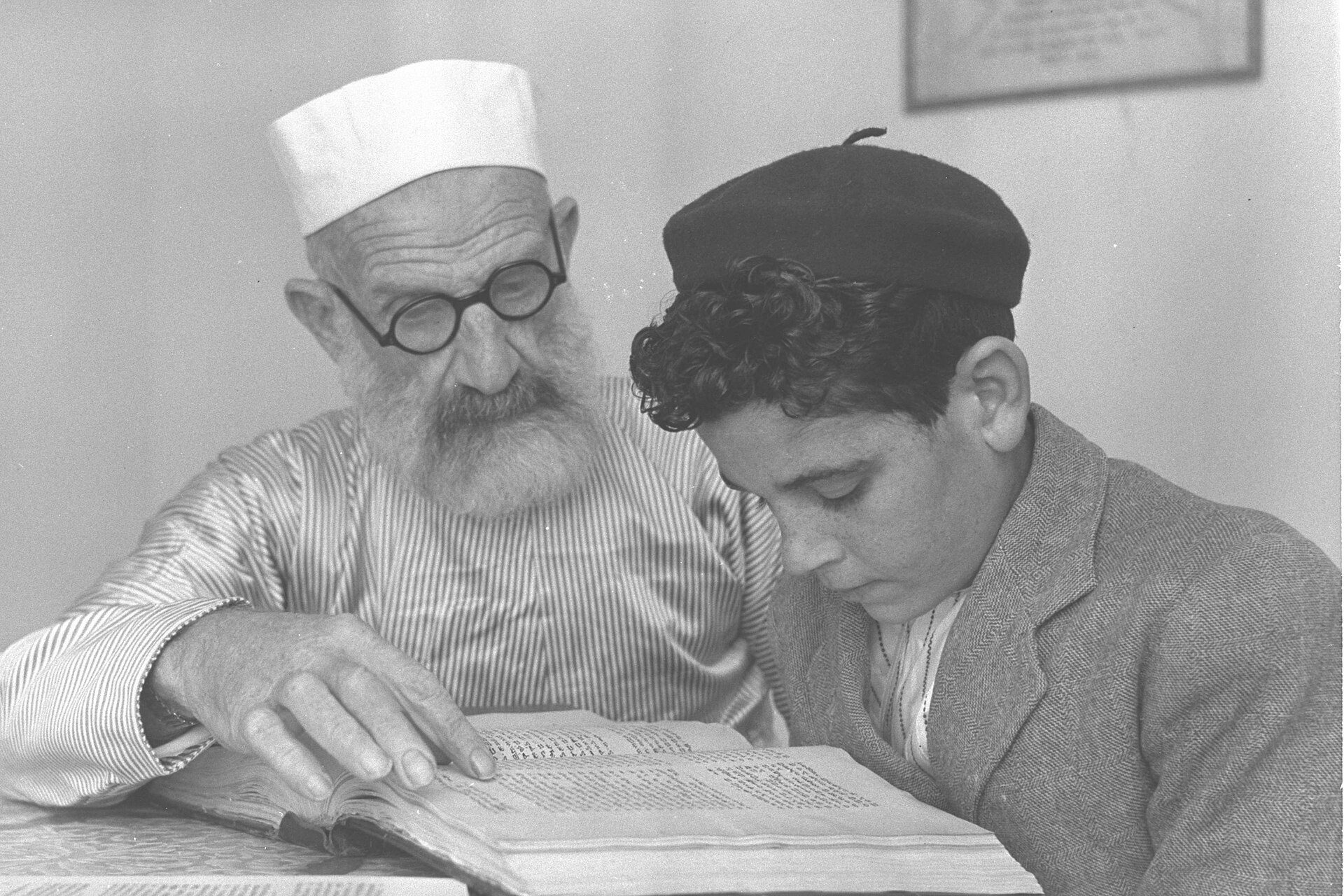 A Samaritan priest in red fez and robes displaying an ancient Torah scroll case