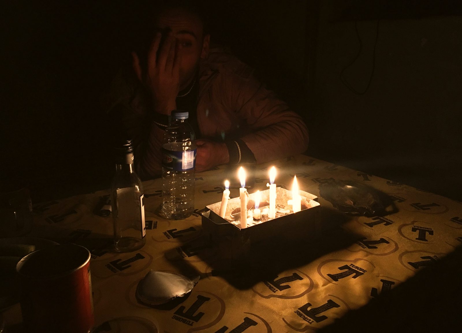 A soldier at a table lit only by a cluster of candles during a power cut in the barrack