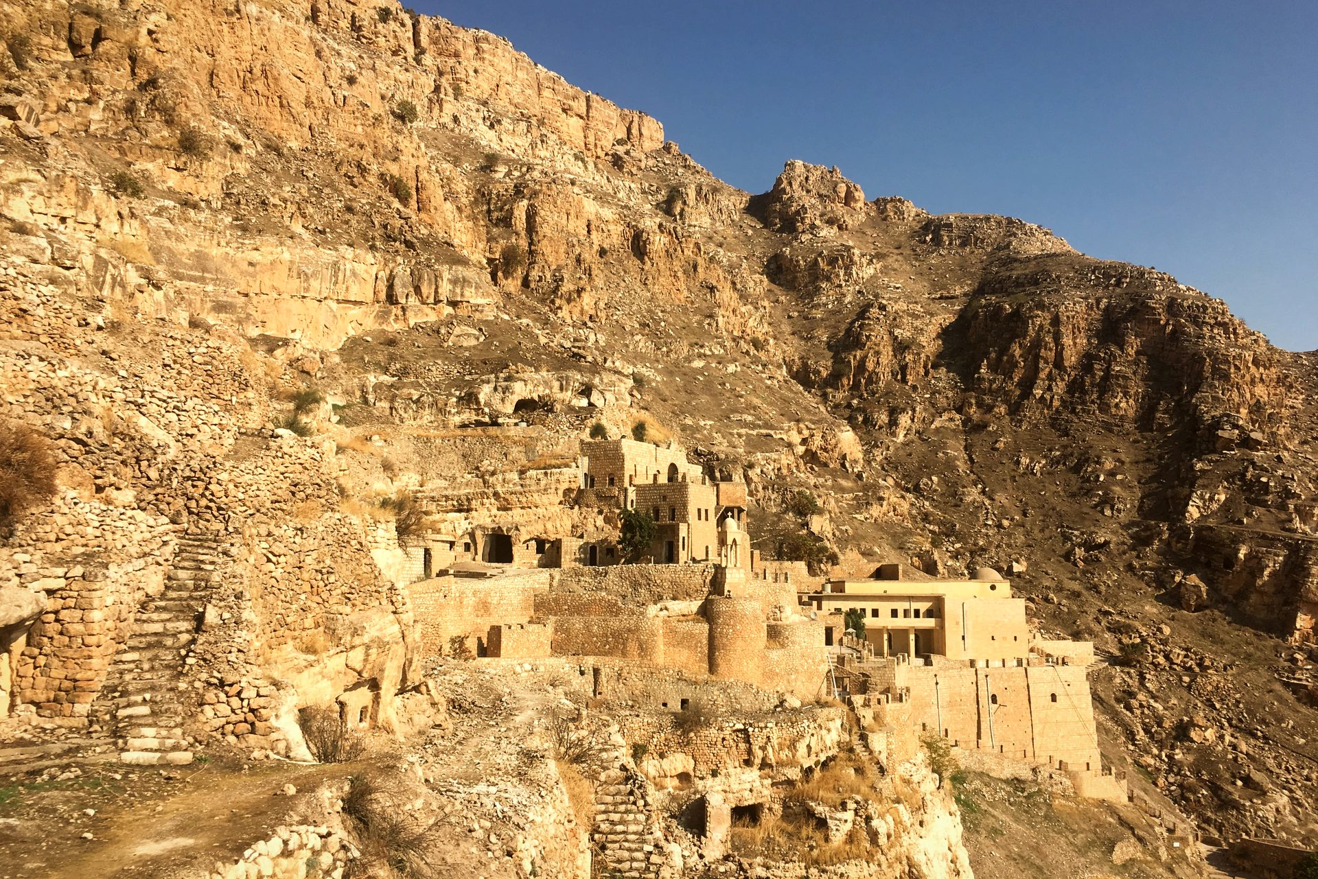 The Rabban Hormizd monastery built into a cliff face above Alqosh, stairways and stone cells climbing the mountain